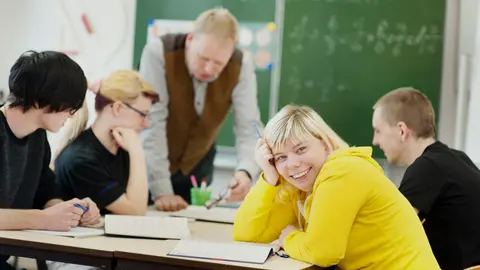 Vier Jugendliche und ein Pädagoge im Klassenraum.
