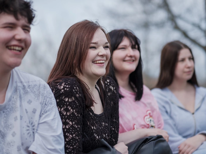 Vier Jugendliche sitzen nebeneinander und lachen